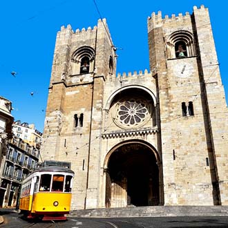 Gele tram voor een kerk in Lissabon